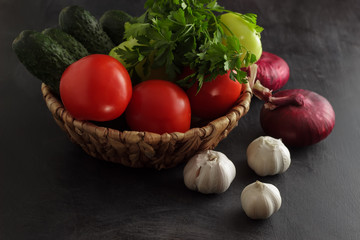 Vegetables tomatoes, cucumbers, onions and garlic with parsley in a basket