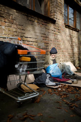 Street life of homeless old man. Tramp and his possessions in shopping cart in the street of the...