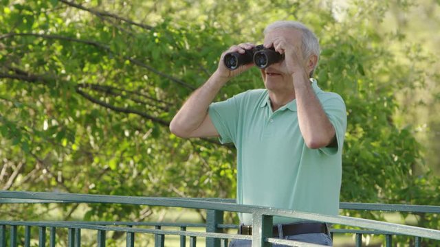 Elderly man using binoculars in the park