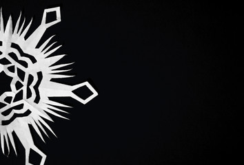 snowflake cut from paper on black background