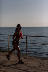 beautiful girl with sports forms sports on the beach, drinking water, jumping, running, doing different exercises