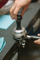 Barista pulling coffee at metal holder for espresso making.
