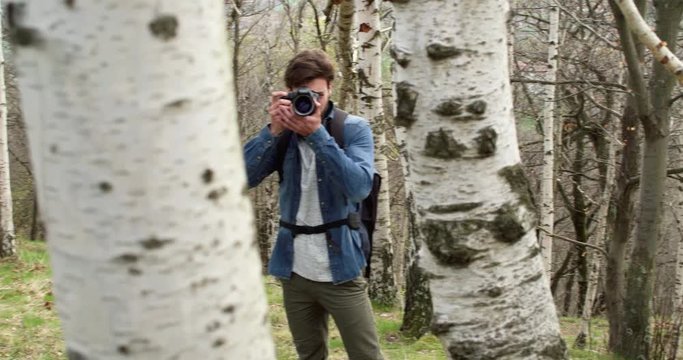 man in woods looking and shoot photos in camera.Following side.Real people Millennial traveller backpacker adult male photographer walking on rural field to shoot photographs in autumn season.4k video