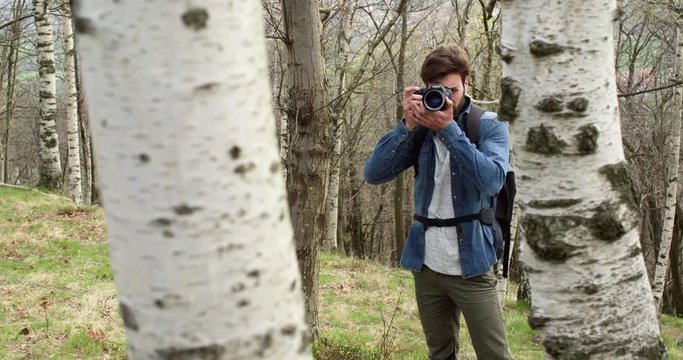 man in woods looking and shoot photos in camera.Following side.Real people Millennial traveller backpacker adult male photographer walking on rural field to shoot photographs in autumn season.4k video