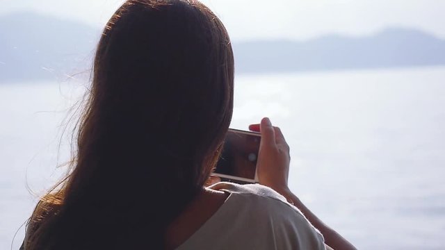 Young brunette woman standing on deck of cruise ship and takes photo with smart phone in slow motion. 1920x1080