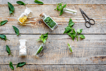 Harvest medicinal herb. Leaves, bottles and sciccors on wooden background top view