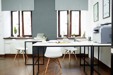 Modern office with several workplaces, chairs and supplies on desks