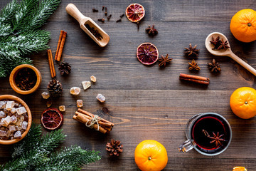 Hot mulled wine or grog cooking for new year celebration with oranges and spices ingredients on wooden background flat lay