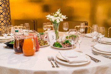 Beautiful fresh flowers on table in wedding day. Bouquet of white eustoma in glass vase on dinner table in restaurant with gold interior