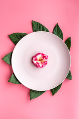Plate, tropical leaf and fruit on pink background top view copyspace