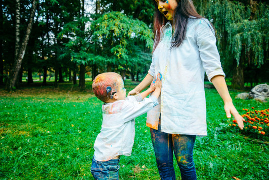 mother with son in holi paints in city park