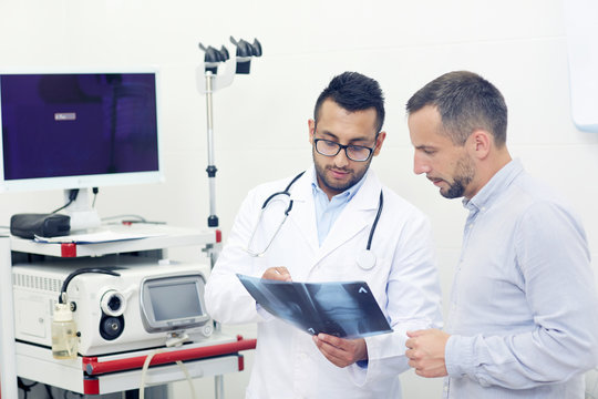 Patient and doctor looking at knee x-ray result in clinical office
