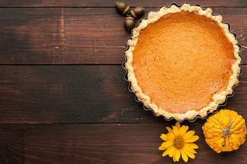 pumpkin homemade pie at wooden background arranged with food ingredients top view