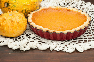 pumpkin homemade pie at wooden background arranged with food ingredients