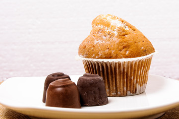 A fragrant and appetizing cupcake with sweets on a white plate