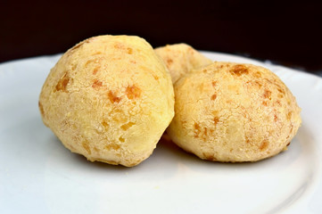 Cheese Bread - brazilian typical food from Minas Gerais known as "Pão de Queijo" on a white plate isolated on black background