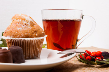 Fresh and fragrant cupcake with sweets and tea on a white background