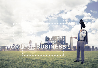 Camera headed man standing on green grass against modern citysca