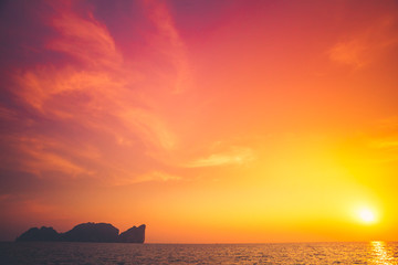 Naklejka na ściany i meble Beautiful tropical sunset in Krabi, Thailand. Dramatic and picturesque evening scene. Ocean and colorful orange cloudy sky in the background. Nature landscape. Travel background. Bright purple toning