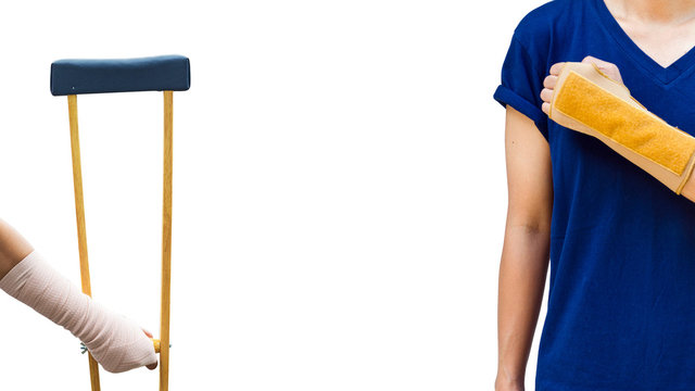 broken arm, injury woman wearing shirt and jeans  with arm splint standing and holding wooden crutches isolated on white.