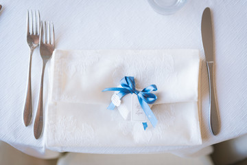 Place card with blue bow and ''with love'' label on a napkin with forks and knife