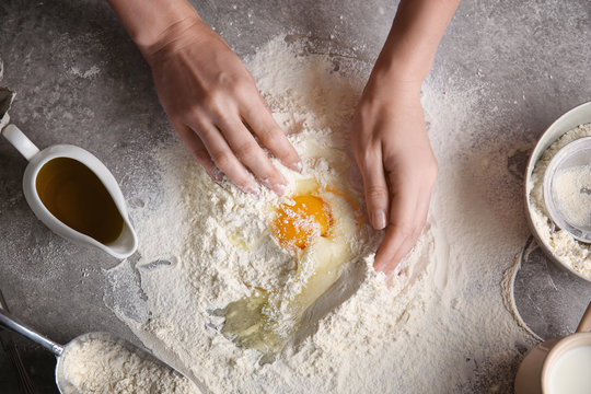 Female chef making dough on kitchen table
