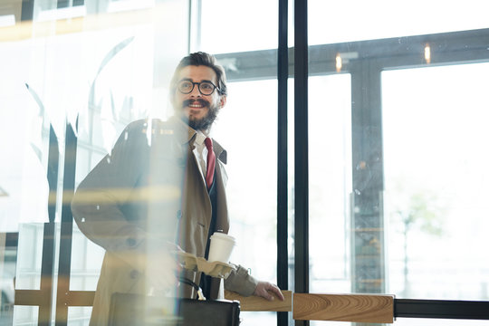 Posh businessman with glass of drink leaving cafe after lunch break