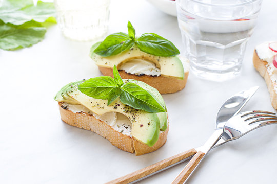 Bruschettas with cream cheese, avocado and basil. Close up