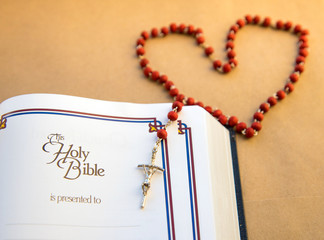 A wooden rosary in the form of a heart on the Bible and place for inscription