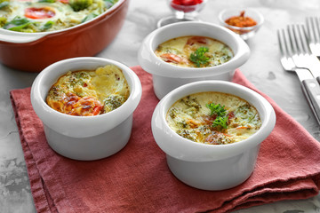 Ramekins with tasty broccoli casserole on table