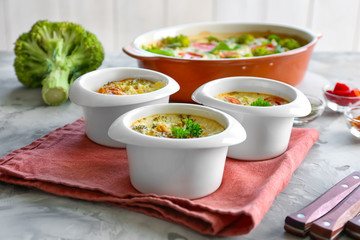Ramekins with tasty broccoli casserole on table