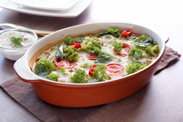 Baking dish with broccoli casserole on table