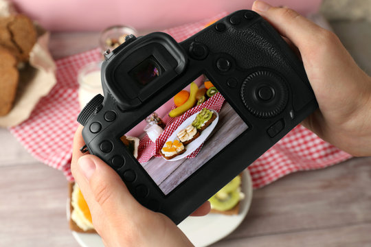 Young woman taking photo of delicious toasts with professional camera