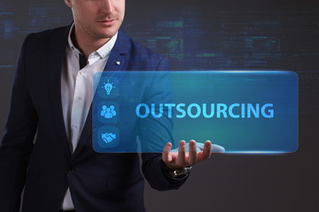 Business, Technology, Internet and network concept. Young businessman working on a virtual screen of the future and sees the inscription: Outsourcing