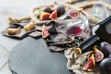 Bottle, corkscrew, glass of red wine, figs on a table