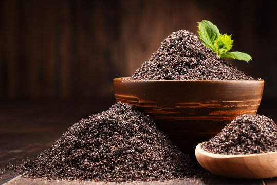 Composition with bowl of poppy seeds on wooden table