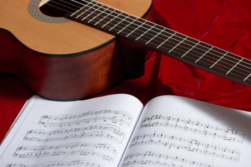 acoustic guitar and music notes on red fabric, close view of objects