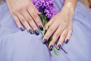 Fototapeta premium Violet aster flowers at hands with black manicure of girl.