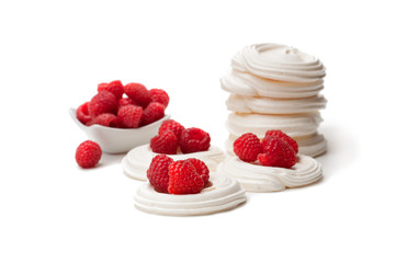 Mini  Pavlova meringue nests with raspberries on isolated on white