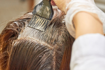 Brush applying dye on hair. Hair of woman close up.