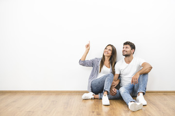 The happy man and woman sit on the background of the white wall