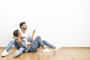 The smile couple sit and gesture on the background of the white wall