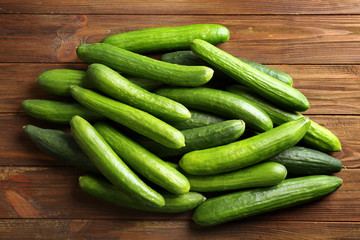Many green fresh cucumbers on wooden background