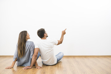 The sitting couple look the empty wall and gesture
