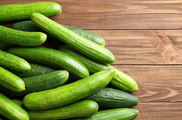 Many green fresh cucumbers on wooden background