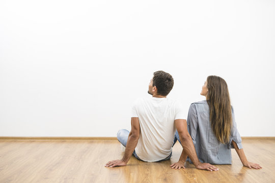 The sitting couple look the empty wall