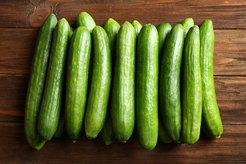 Many green fresh cucumbers on wooden background