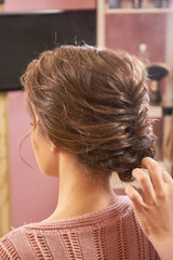 Fototapeta premium Hand of stylist, braided hairdo. Woman with brown hair.