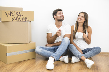 The happy couple hold cups of coffee near carton boxes