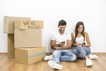 The happy couple phone near boxes on the background of the white wall